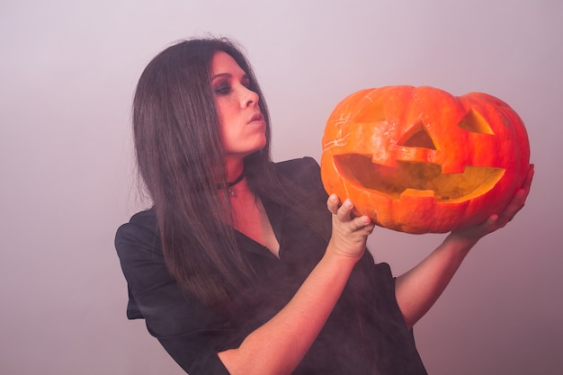 Frau als Hexe steht mit dem Kürbis Halloween- und Karnevalskonzept.