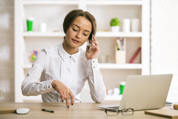 Frau am Arbeitsplatz am Telefon sprechen