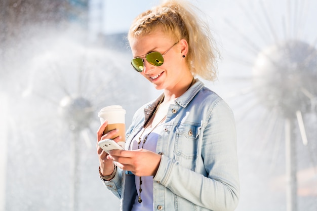 Frau am brunnen mit telefon und kaffee