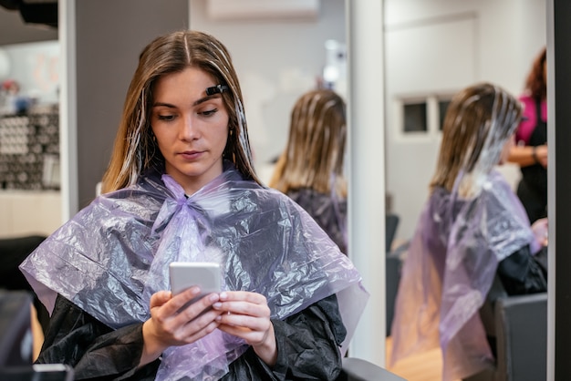 Frau am Handy bei der Aufwartung mit dem Haar gefärbt