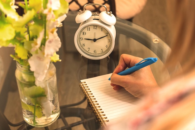 Frau am Morgen schreibt in Notizbuch persönliches Tagebuchkonzept mit gemütlichem Arbeitsplatz über Schulteransicht Foto