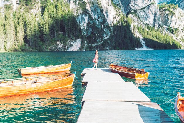 Frau am Pier mit Holzbooten im Bergsee in Italien