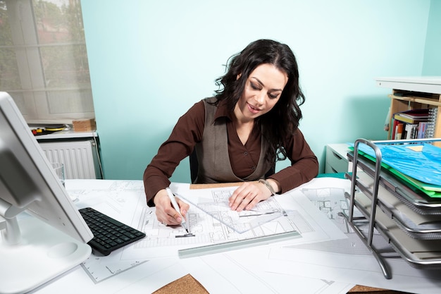 Frau am Schreibtisch mit Blaupausen vor ihr. Arbeiten an neuen Projekten. Architektur und Design
