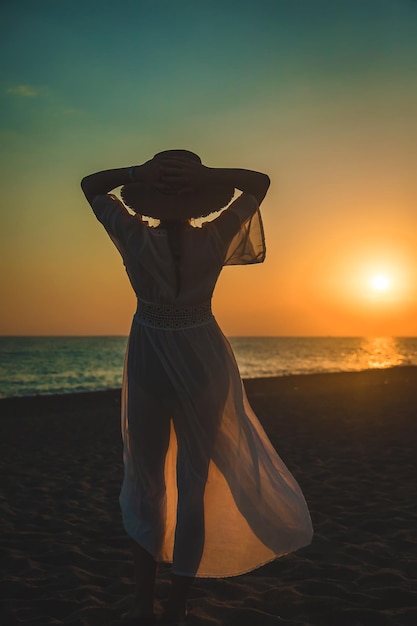 Frau am Strand bei Sonnenuntergang. Selektiver Fokus.