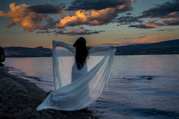 Frau am Strand gegen den Himmel beim Sonnenuntergang