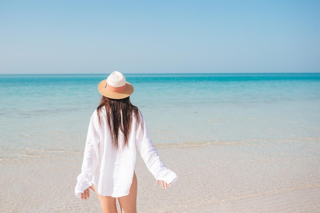 Frau am Strand genießt die Sommerferien mit Blick auf das Meer