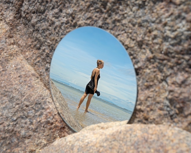 Foto frau am strand im sommer posiert mit rundem spiegel