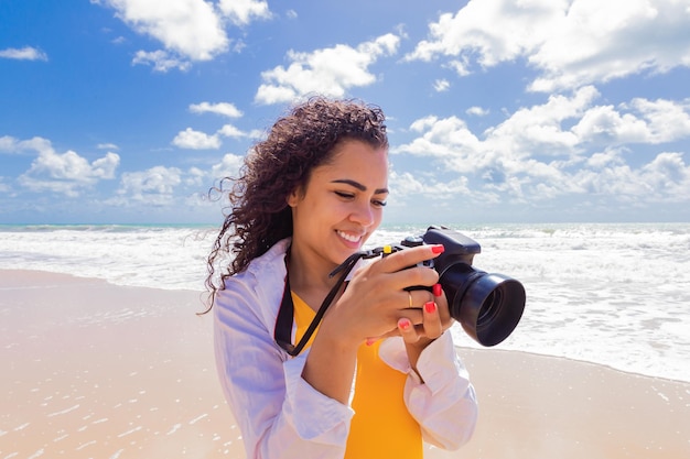 Frau am Strand im Urlaub fotografieren im Sommer Junge Frau mit Kamera am Strand