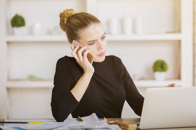 Frau am Telefon mit Laptop