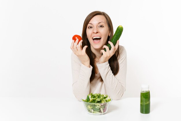 Frau am Tisch mit grünen Detox-Smoothies, frischer Salat in Glasschüssel, Tomate, Gurke isoliert auf weißem Hintergrund. Richtige Ernährung, vegetarisches Essen, gesunder Lebensstil, Diätkonzept. Platz kopieren.