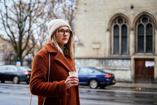 Frau an der Stadtstraße mit Kaffeetasse