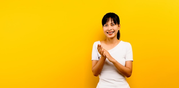 Frau applaudiert Asiatische Frau klatscht nach einer Konferenzpräsentation über isoliertem gelben Hintergrund mit Kopierraum