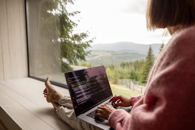 Frau arbeitet am Laptop im Haus in den Bergen