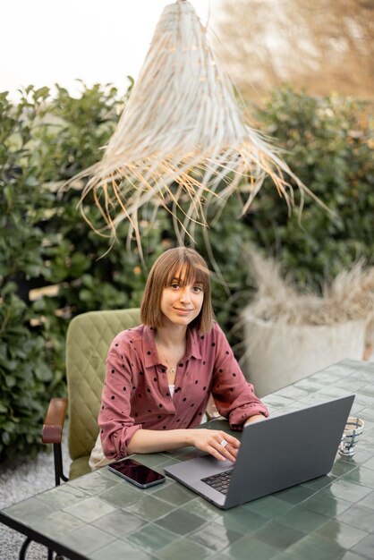 Frau arbeitet am Laptop online im Garten im Freien