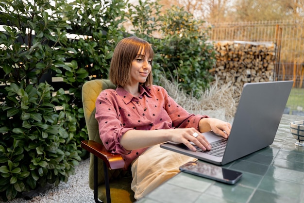 Frau arbeitet am Laptop online im Garten im Freien
