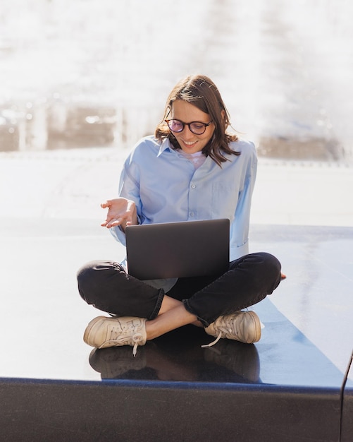 Frau arbeitet im Sommer an Laptop im Freien Geschäftsperson sitzt am Brunnen