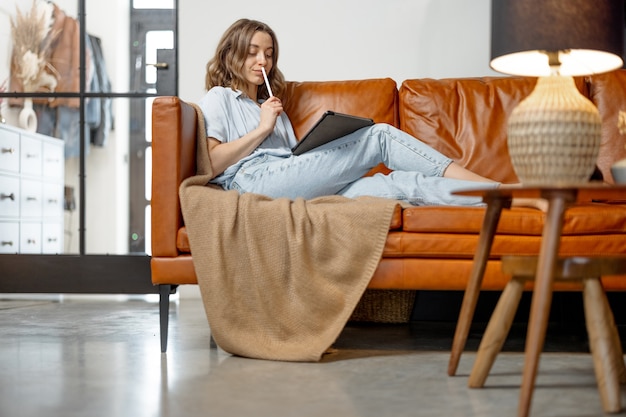 Frau arbeitet mit digitalem Tablet von zu Hause auf dem Sofa