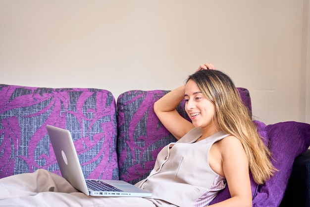 Frau arbeitet mit einem Laptop auf dem Sofa zu Hause