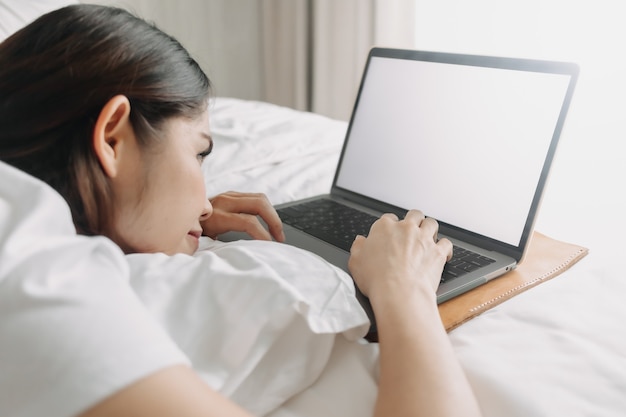 Frau arbeitet mit Laptop auf dem Bett im Konzept der Workation