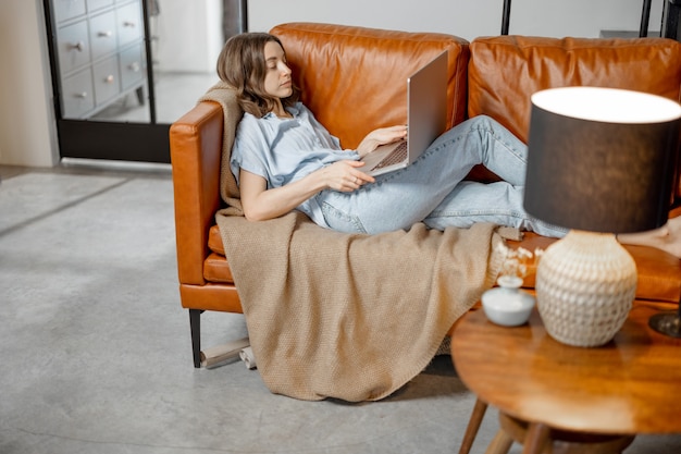 Frau arbeitet mit Laptop von zu Hause auf Sofa