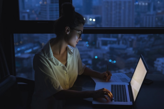 Frau arbeitet mit Laptop zu Hause während der Nacht.