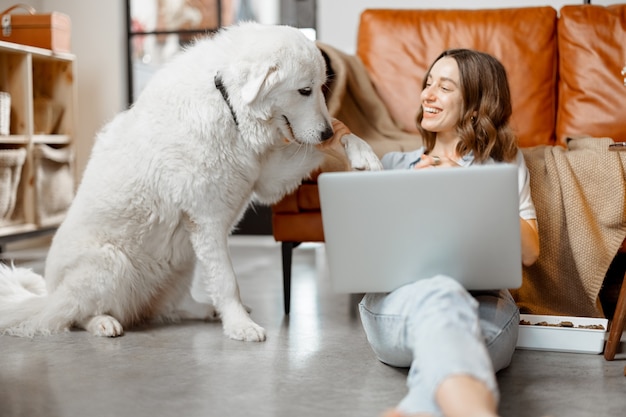 Frau arbeitet zu Hause und sitzt mit Hund