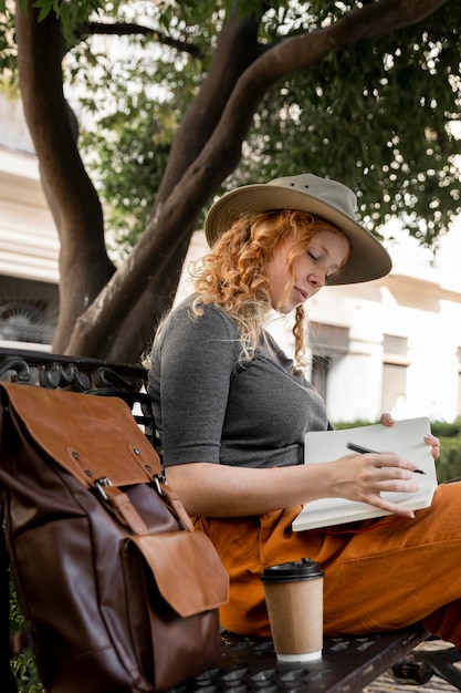 Foto frau auf bank, die im tagebuch schreibt