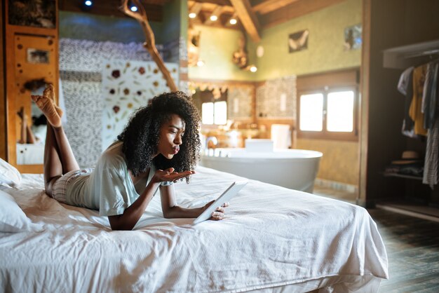 Frau auf dem Bett mit Tablette