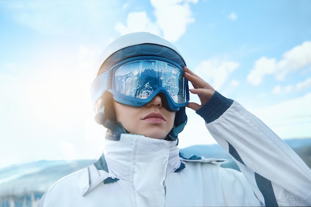 Frau auf dem Hintergrund der Berge und des blauen SkyA-Gebirges, das sich in der Skimaske widerspiegelt