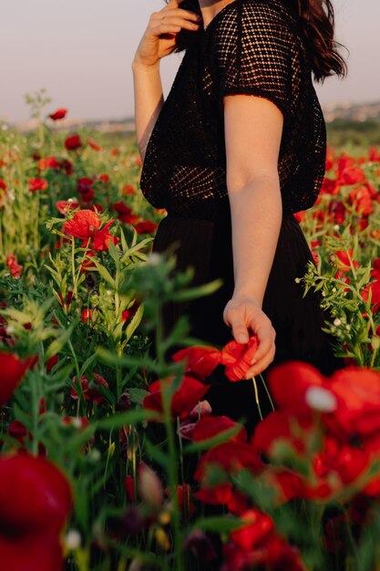 Frau auf dem Mohnblumenfeld auf Sonnenuntergangkopienraum