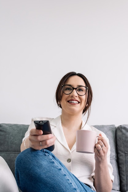 Frau auf dem Sofa mit der TV-Fernbedienung