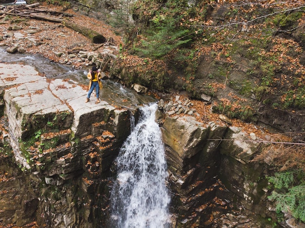 Frau auf der Klippe, die den Wasserfall betrachtet und die Aussicht genießt