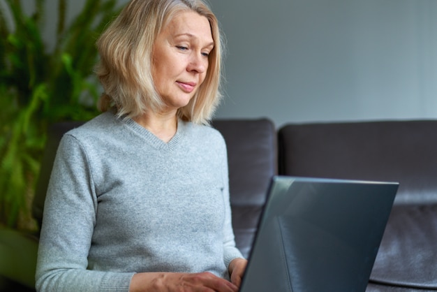 Frau auf einem Sofa zu Hause konzentriert, wie sie an einem Laptop arbeitet.