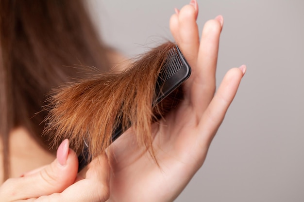 Frau auf einem weißen Hintergrund mit einem Kamm für das Haar das Haarproblem