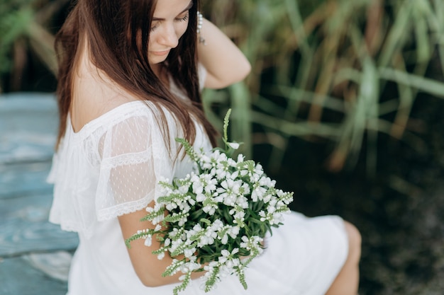 Frau auf einer hölzernen Brücke durch den See mit einem Blumenstrauß von Wildblumen