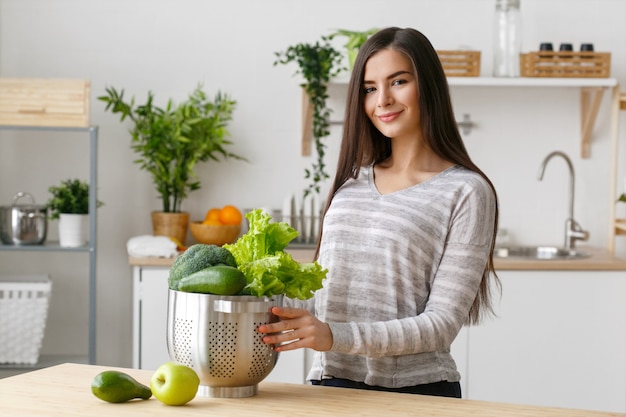 Frau auf Küchenhaus mit grünem Gemüsekochen. Helthy Hauptnahrungsmitteldiätvitamine junge und schöne Frau. Studioaufnahme.