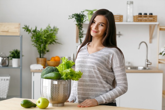 Frau auf Küchenhaus mit grünem Gemüsekochen. Helthy Hauptnahrungsmitteldiätvitamine junge und schöne Frau. Studioaufnahme.