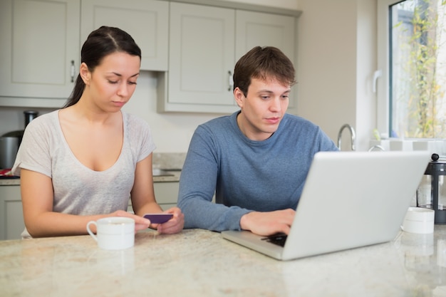 Frau auf Smartphone mit Mann auf Laptop