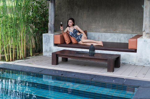 Frau auf Stuhl und ein Glas im Swimmingpool halten