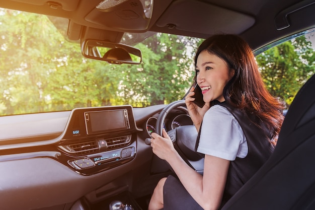 Frau Auto fahren und am Handy sprechen