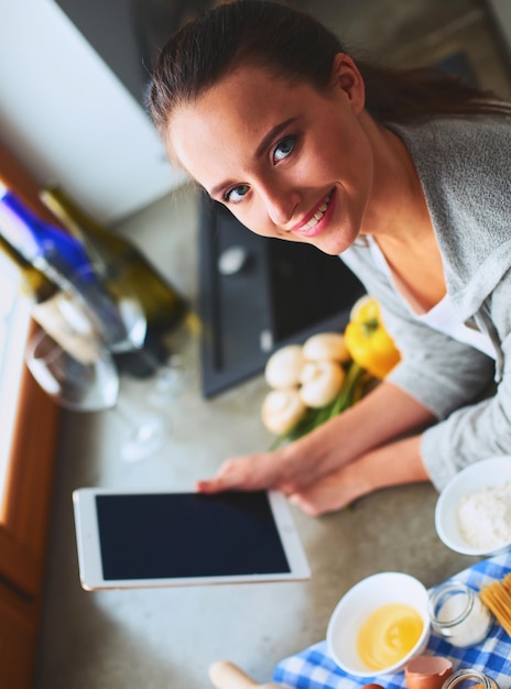 Frau backt zu Hause nach Rezept auf einem Tablet