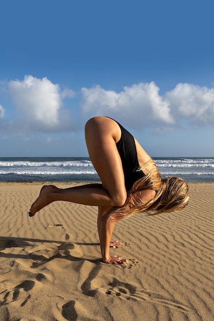 Frau balanciert beim Yoga am Strand