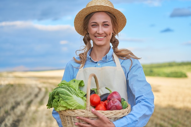 Frau Bauer Strohhut Schürze stehend Ackerland lächelnd Weibliche Agronomin Fachlandwirtschaft Agrobusiness Glücklich positive kaukasische Arbeiter landwirtschaftlichen Bereich