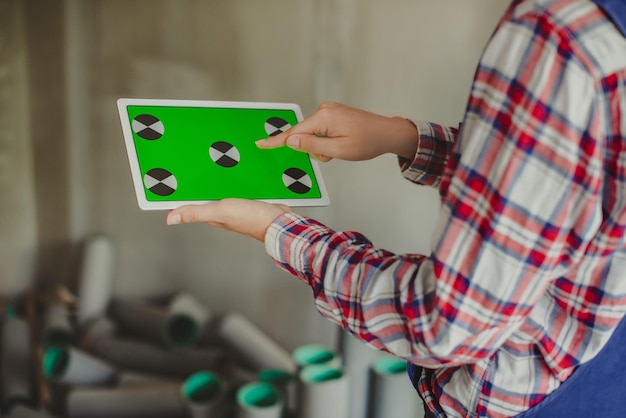 Frau Bauleiterin mit Tablet-Gerät mit grünem Bildschirm und Touchscreen mit Finger