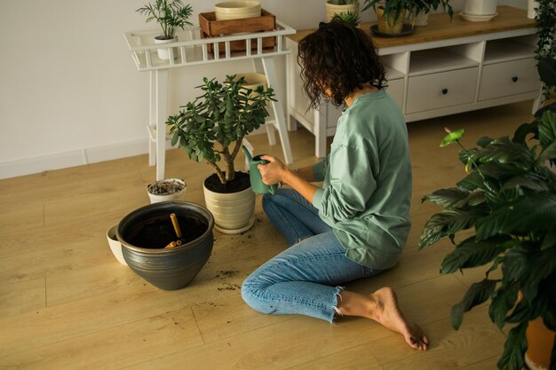 Frau baut zu Hause Topfpflanzen an, bewässert und kümmert sich um Blumen, Gartenarbeit und Zimmerpflanzenpflege