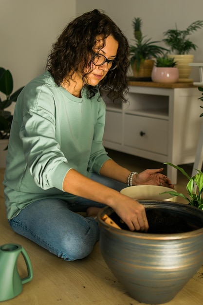 Frau baut zu Hause Topfpflanzen an, bewässert und kümmert sich um Blumen, Gartenarbeit und Zimmerpflanzenpflegekonzept