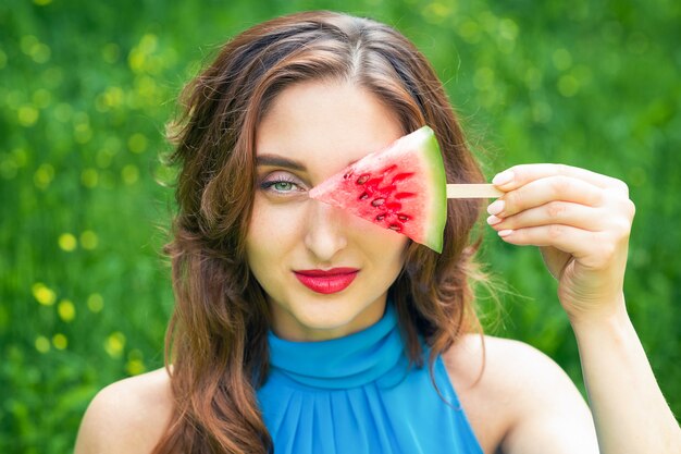 Frau bedeckt Auge mit Wassermelone.