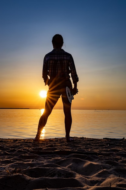 Frau bei Sonnenuntergang mit einer Ukulele