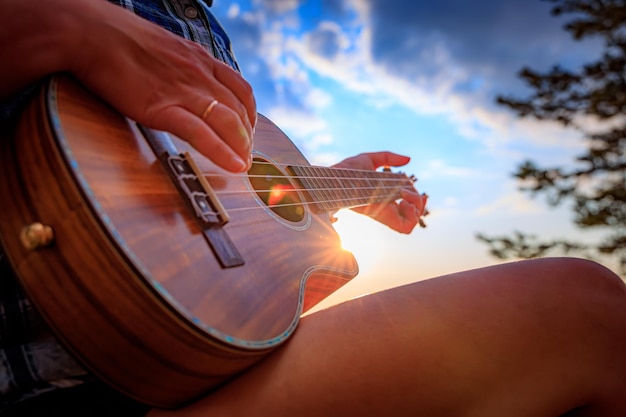 Frau bei Sonnenuntergang mit einer Ukulele