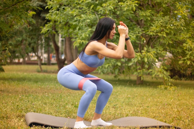 Frau beim Fitnesstraining in der Natur mit Widerstandsgummiband. Fitness-Kaugummi